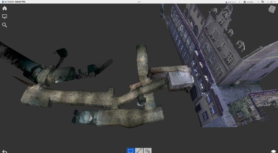 Das Bild zeigt eine digitale 3D-Darstellung eines Gebäudes und eines darunter liegenden Keller- oder Tunnelnetzes. Rechts ist die Außenansicht eines mehrstöckigen Gebäudes mit Fenstern und architektonischen Details zu sehen, während links ein komplexes System aus gewölbten Gängen und Räumen dargestellt ist. Die Strukturen wirken wie ein Scan oder Modell, bei dem die Oberflächen texturiert, aber teilweise unvollständig dargestellt sind.