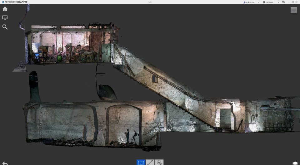Das Bild zeigt eine digitale 3D-Darstellung eines Gebäudes mit einem Schnitt durch die oberen Räume und die darunterliegenden Kelleranlagen. Im oberen Bereich sind Einrichtungsgegenstände und ein Raum mit verschiedenen Objekten erkennbar, während darunter ein steiler Treppenabgang in weitläufige, gewölbte Kellerstrukturen führt. Die Kellerbereiche sind detailliert dargestellt und zeigen mehrere miteinander verbundene Räume mit unterschiedlichen Höhen und Formen.