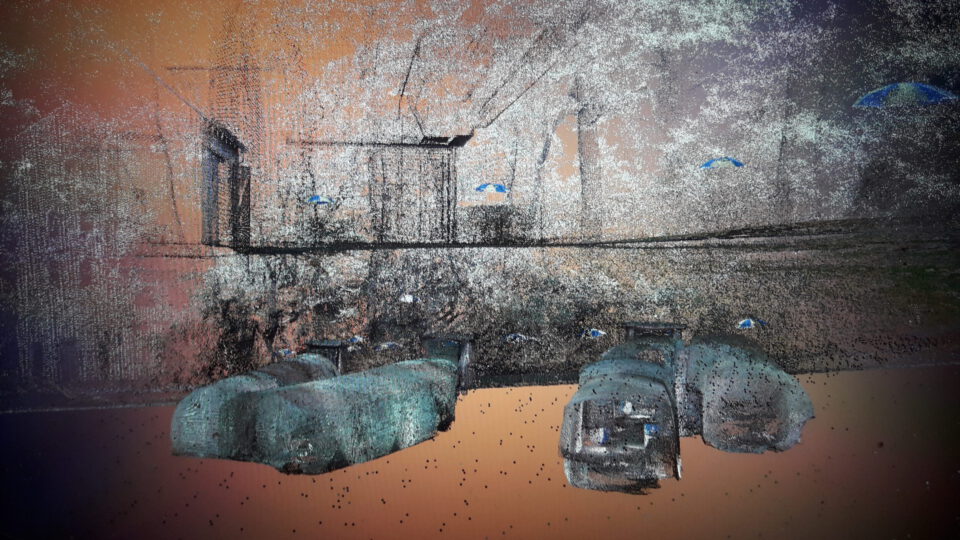 Das Bild zeigt eine digitale Punktwolke-Darstellung, die aus Laserscandaten erstellt wurde und einen unterirdischen Kellerbereich sowie die darüberliegende Oberfläche abbildet. Unten sind mehrere gewölbte Kellerstrukturen erkennbar, die durch ihre Form und Position deutlich hervortreten. Darüber ist eine diffuse Darstellung der Gelände- oder Straßenoberfläche mit zahlreichen Punkten und Markierungen zu sehen, was die räumliche Lage der Keller im Verhältnis zur Umgebung verdeutlicht.
