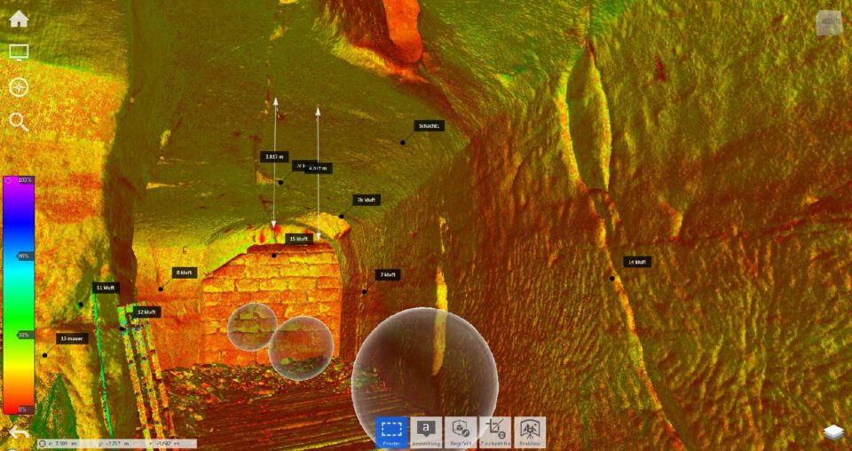 Das Bild zeigt eine farblich codierte 3D-Darstellung eines unterirdischen Hohlraums oder Tunnels mit deutlich erkennbaren Wand- und Deckenstrukturen. Mehrere markierte Punkte und Messlinien weisen auf Risse, Abstände und Auffälligkeiten hin. Die Darstellung wirkt wie eine technische Analyse zur Bauwerksprüfung oder Schadenserfassung.