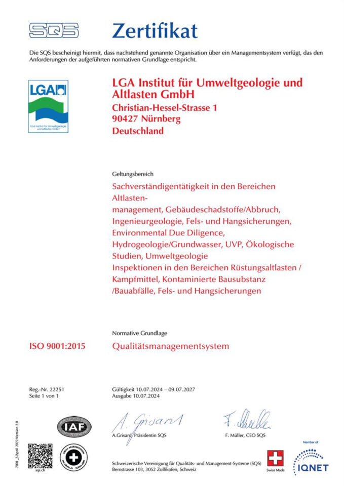 Das Bild zeigt eine einzelne, hochformatige Zertifikatsseite mit klarer Gliederung und überwiegend schwarzer und roter Schrift auf weißem Hintergrund. Oben sind Logos platziert, darunter folgen strukturierte Textbereiche zu Geltungsbereich, Norm und Gültigkeit. Im unteren Bereich befinden sich mehrere Prüfsiegel, ein QR-Code sowie handschriftliche Unterschriften.